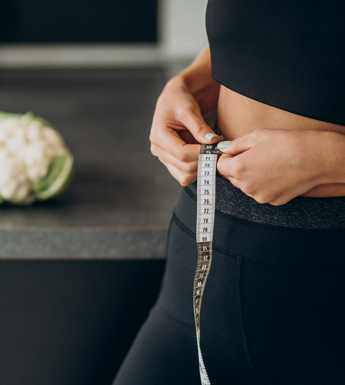 A woman measuring her waist with a tape measure