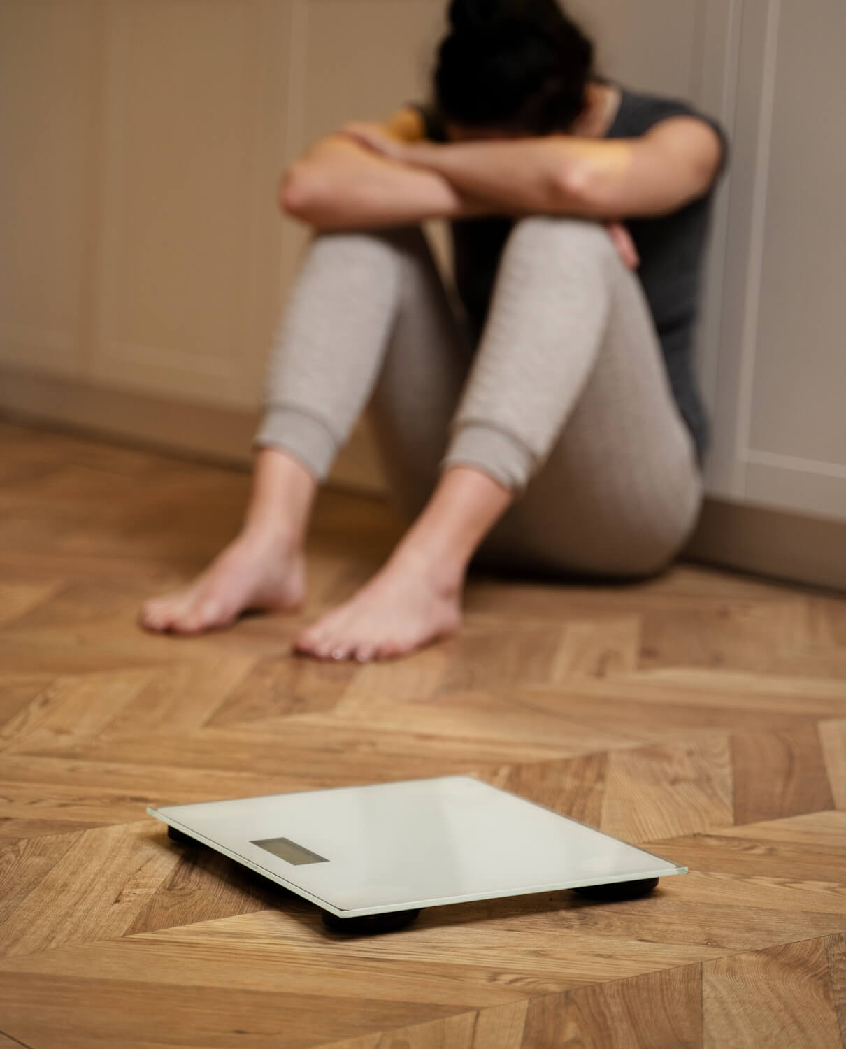 A woman seated beside a a bathroom scale
