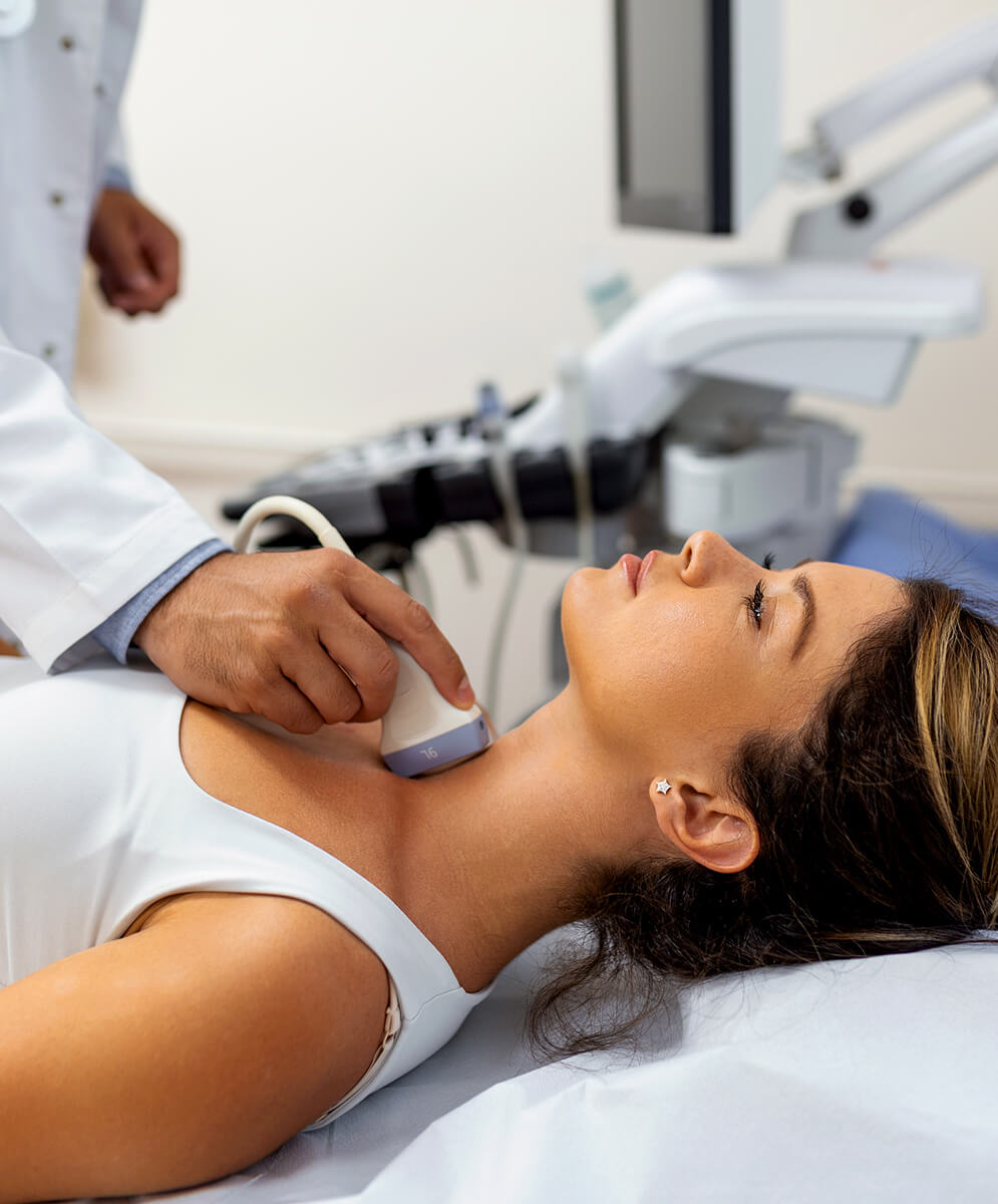 A doctor examining a woman's thyroid area on her neck