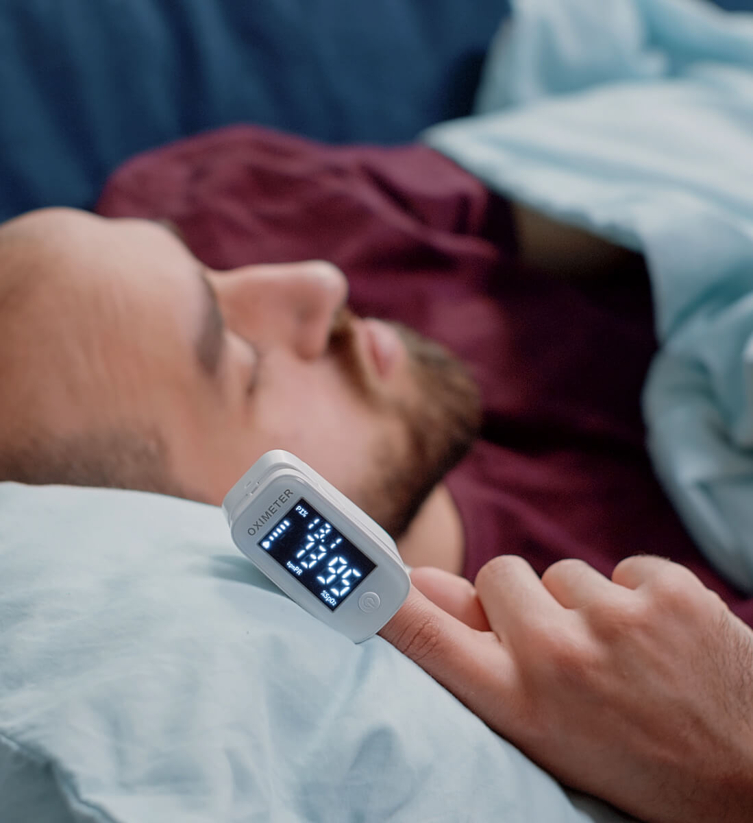 A man sleeping with an oxygen monitor attached to his finger