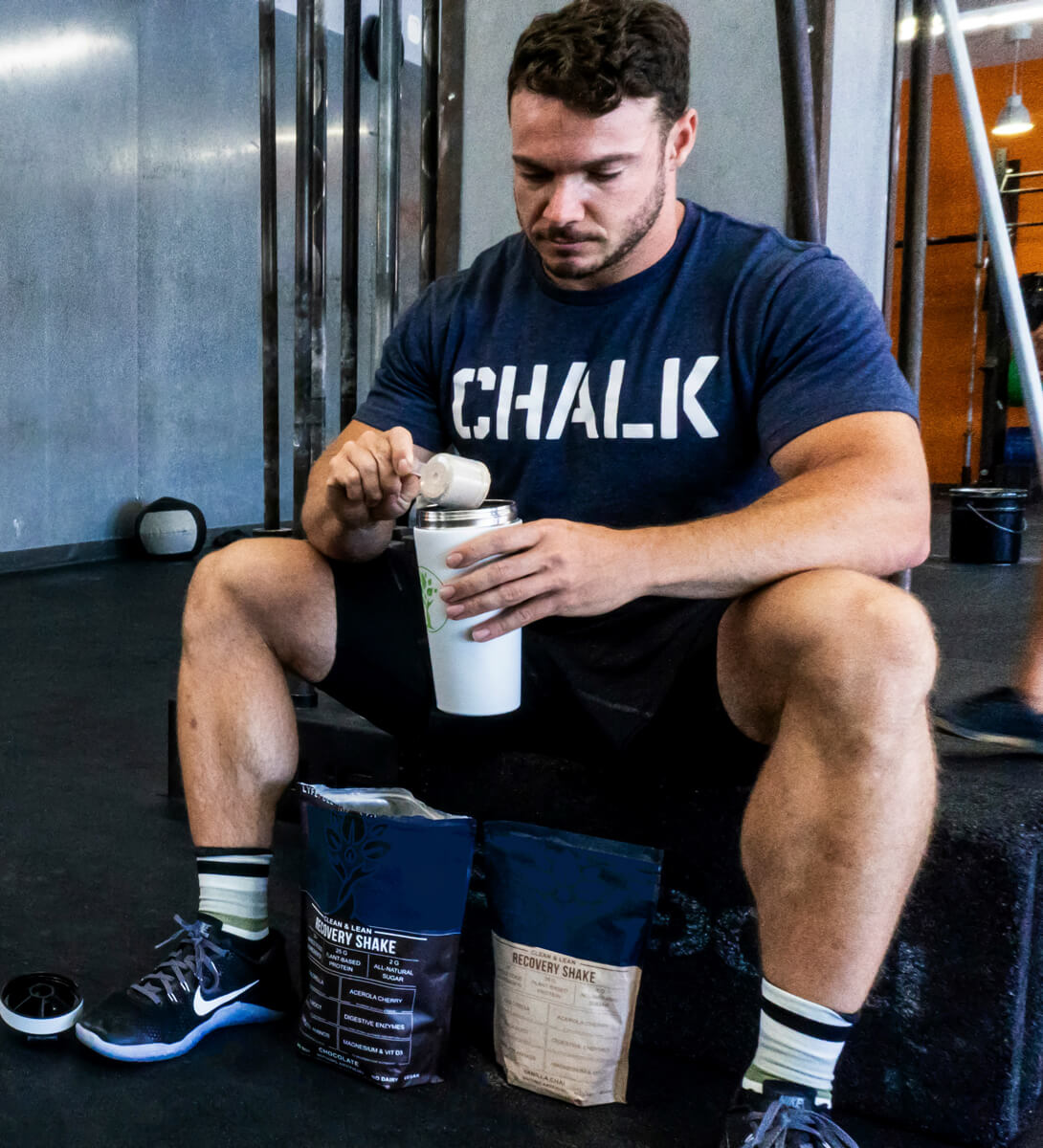 Muscular man taking a break after working out in the gym to prepare his protein shake